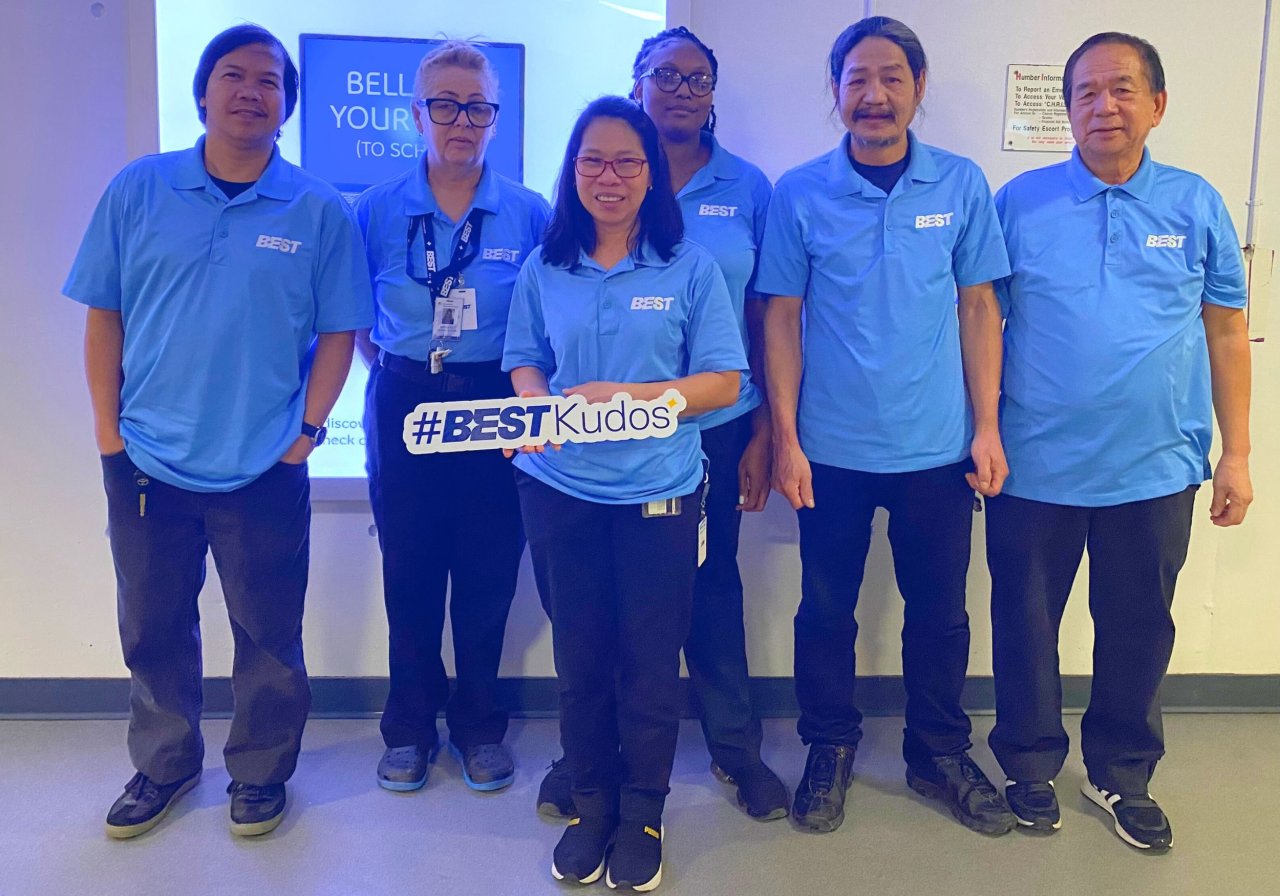 Team posing with a Kudos sign to recognize achievements.